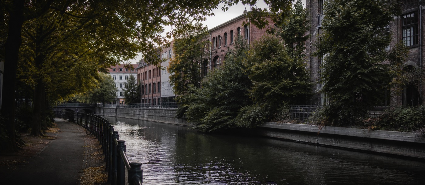 A quiet tree-lined path beside old brick buildings in Berlin